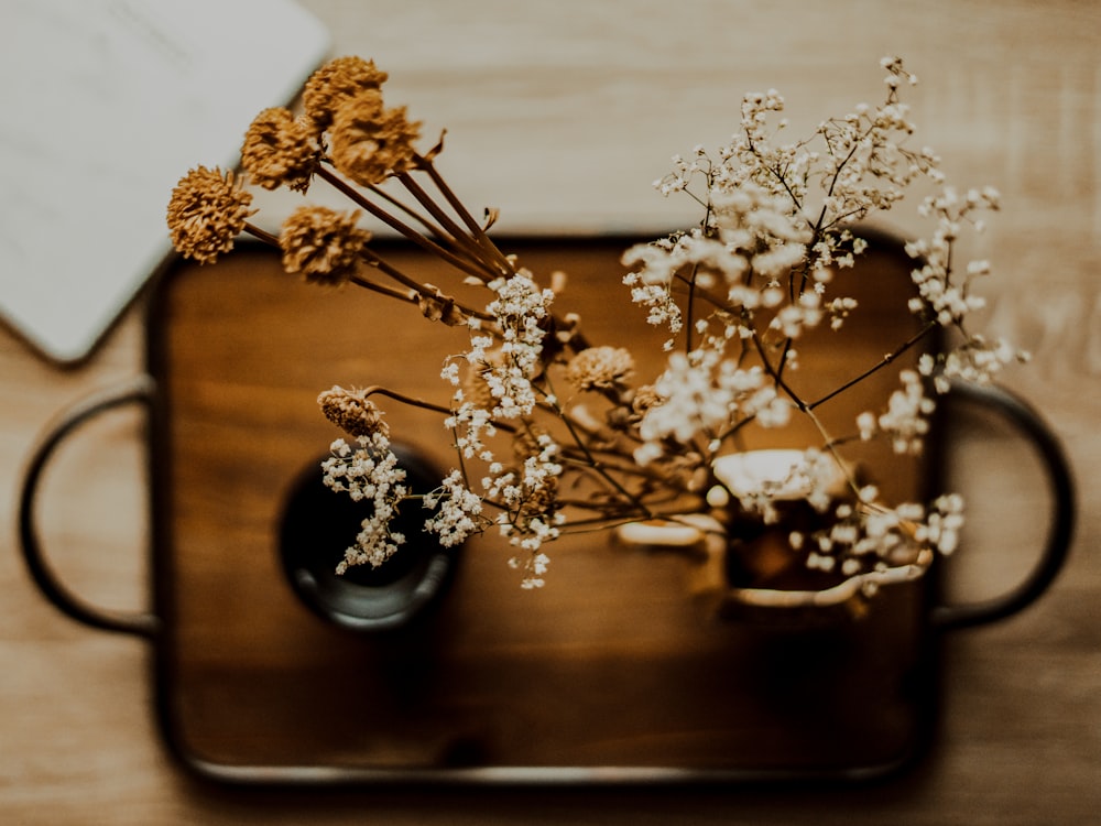 a wooden tray holding a vase with flowers in it