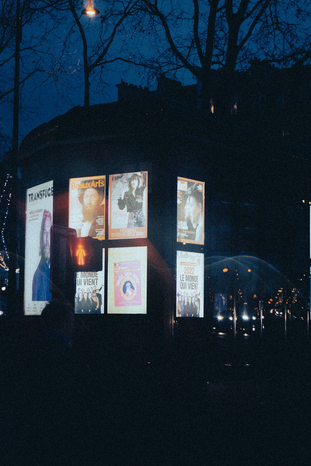 a bus stop covered in posters and lights at night