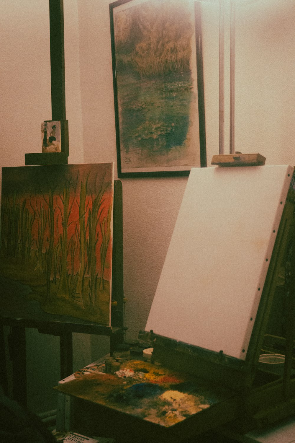 an easel with a painting on it in front of a window
