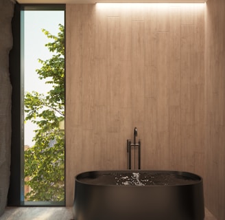 a large black bath tub sitting in a bathroom next to a window