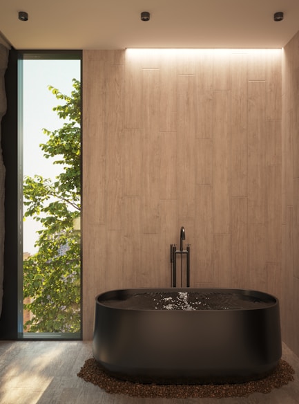 a large black bath tub sitting in a bathroom next to a window