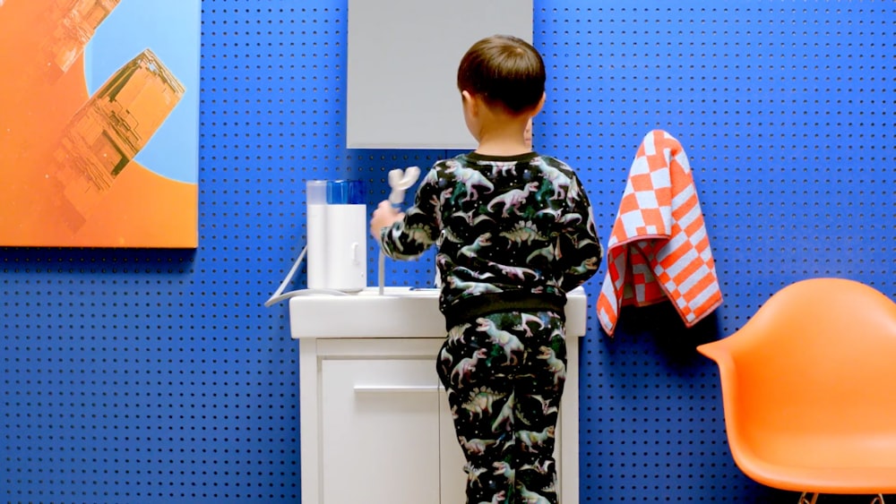 a young boy standing in front of a bathroom sink