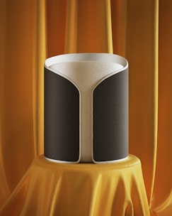 A sleek black party speaker with orange LED lights glowing, set up in a lively living room.