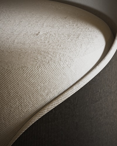 Close-up of a textured fabric swatch in soft beige tones, highlighting the quality and detail of arcélle’s materials.