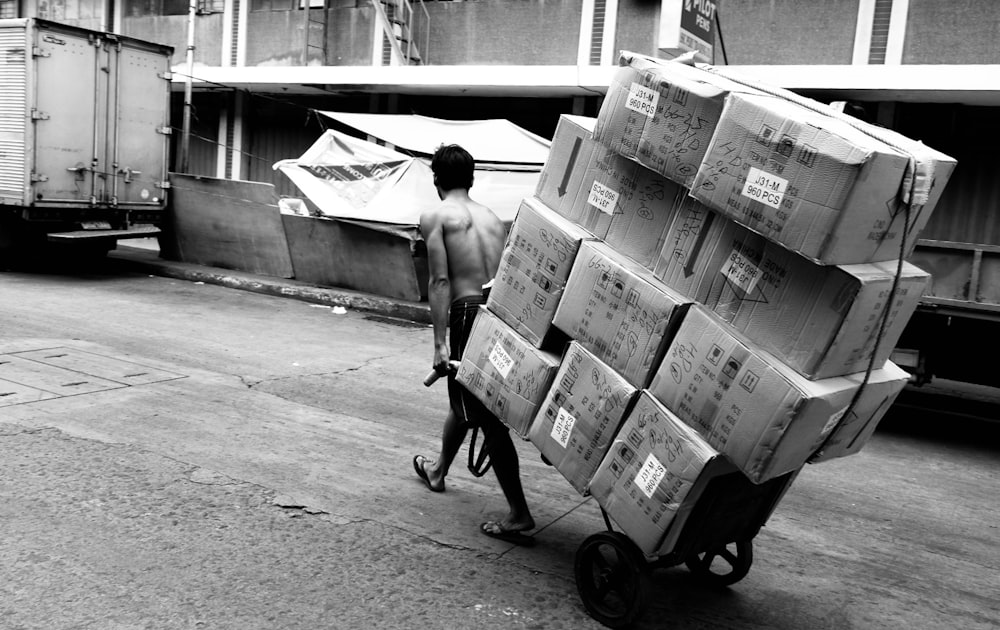 a man pushing a cart full of boxes down a street