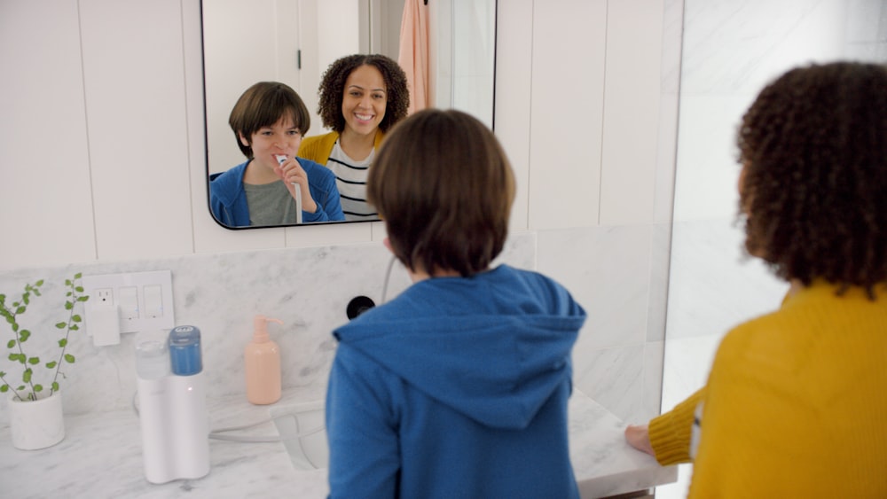 a woman brushing her teeth in front of a mirror