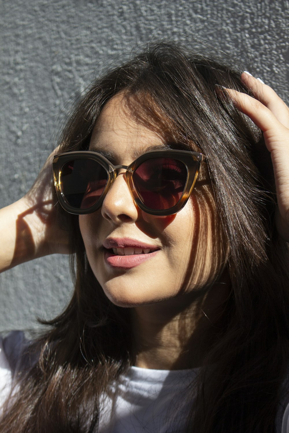 a woman wearing sunglasses and a white shirt