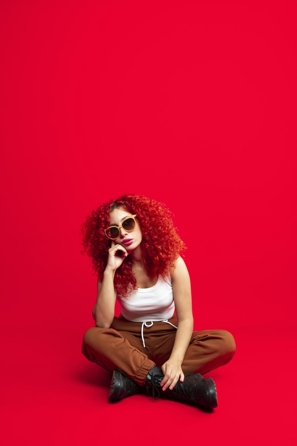 a woman with red hair and sunglasses sitting on the floor