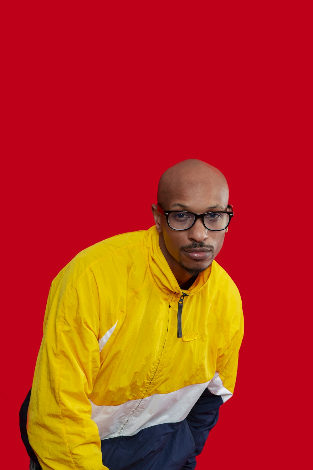 a man with a bald head wearing a yellow jacket