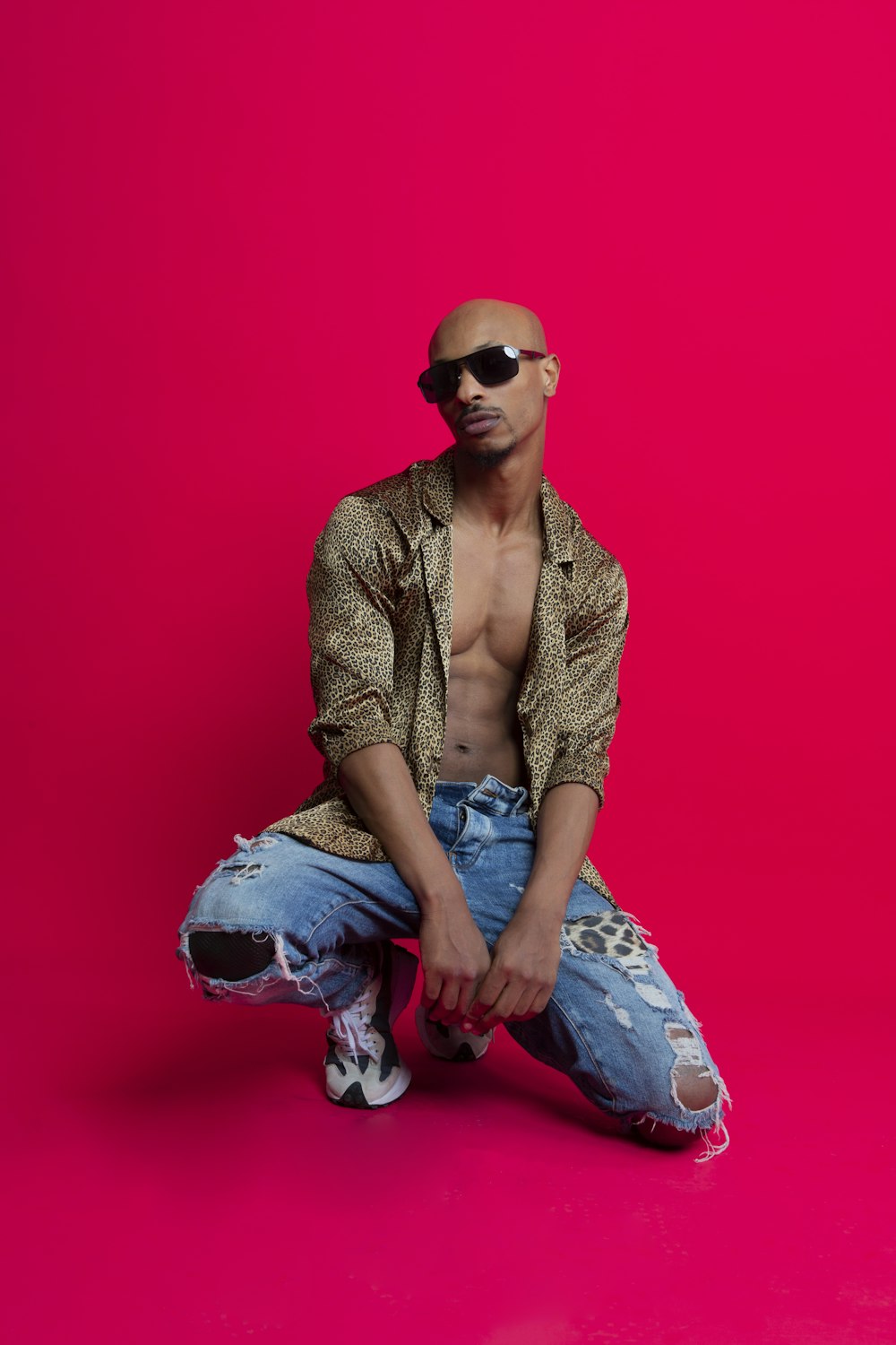 a man with no shirt sitting on a pink background