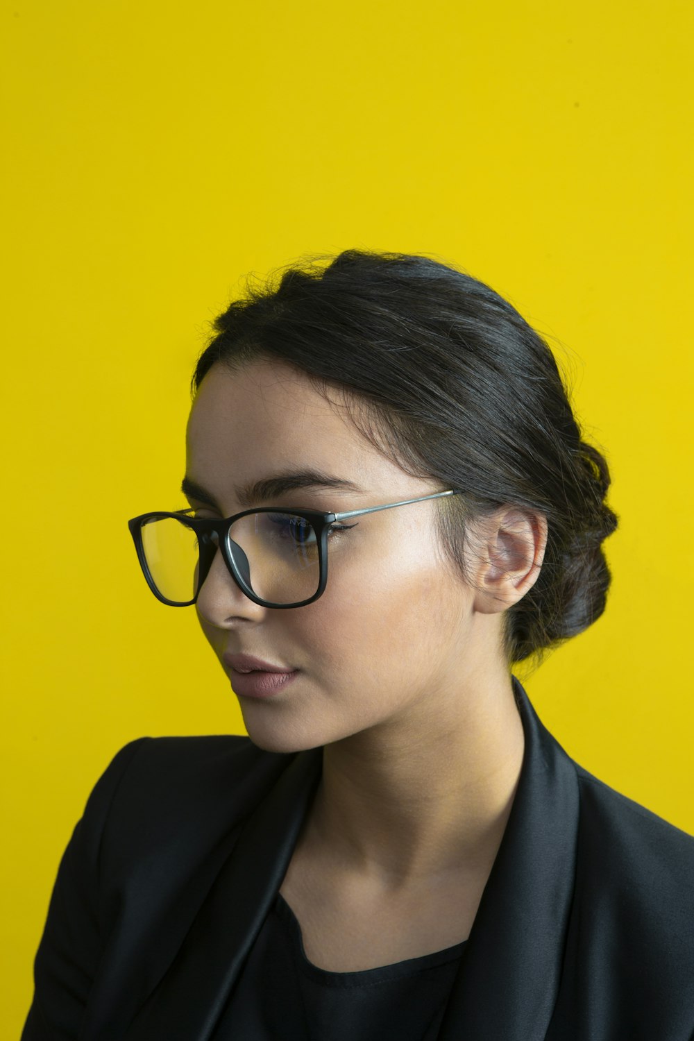 a woman wearing glasses against a yellow background
