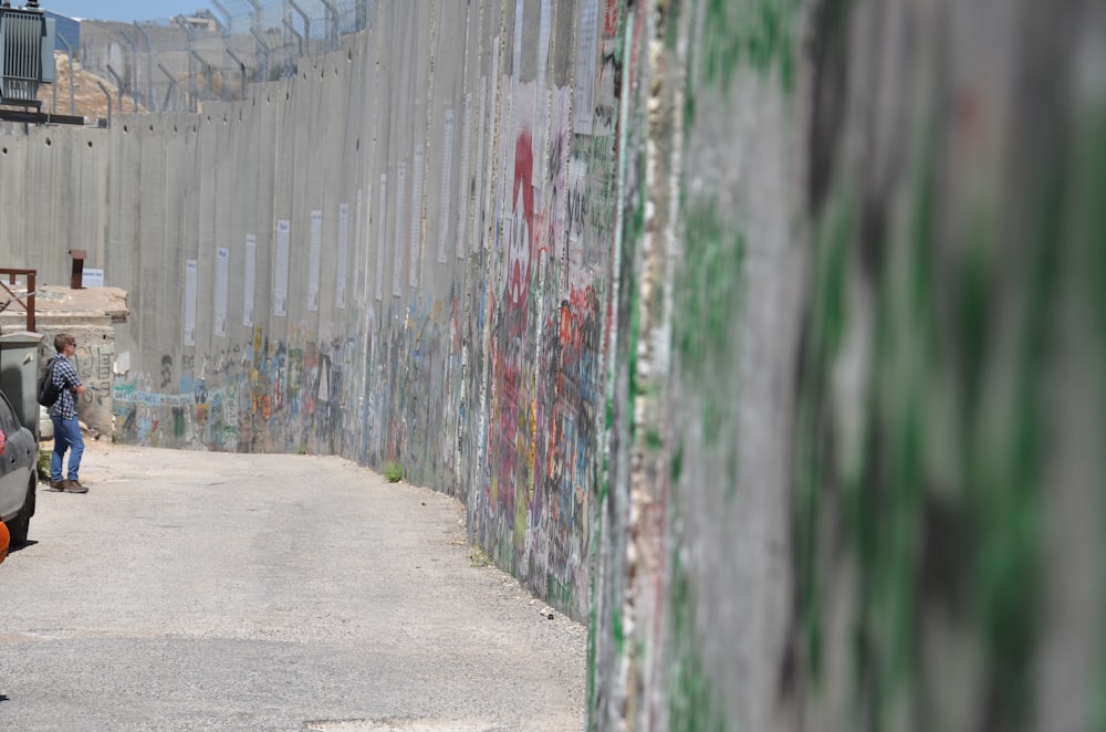 a man standing next to a wall with graffiti on it