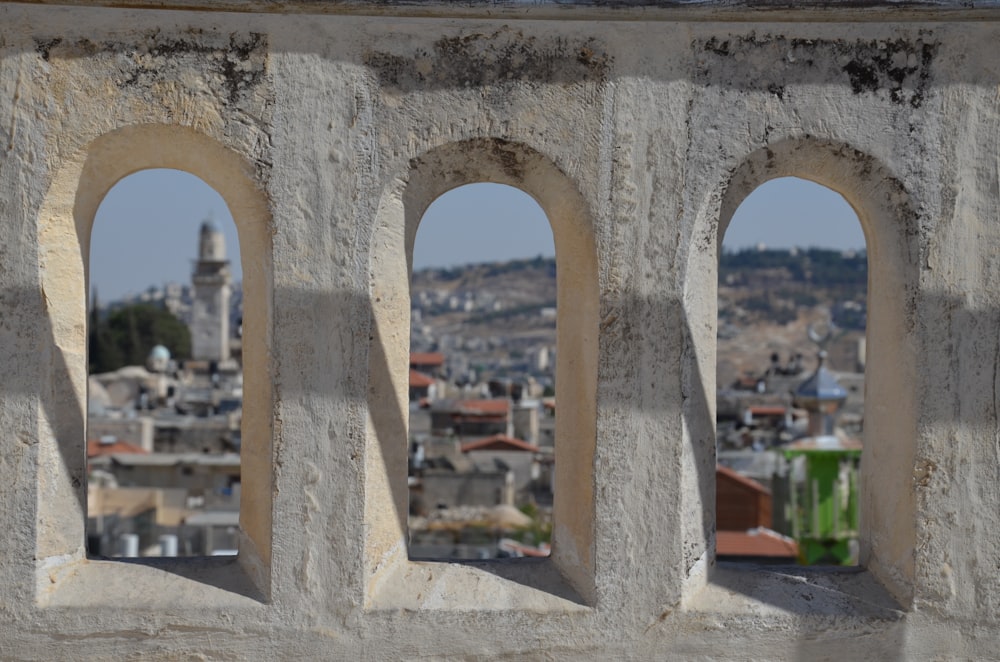 uma vista de uma cidade através de três janelas arqueadas