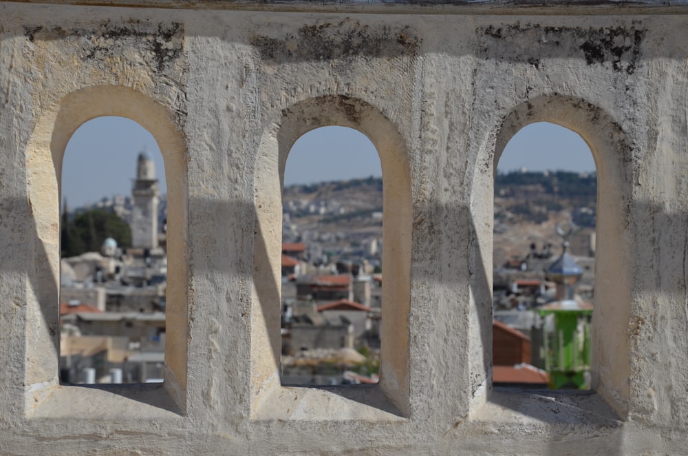 Une vue d’une ville à travers trois fenêtres cintrées