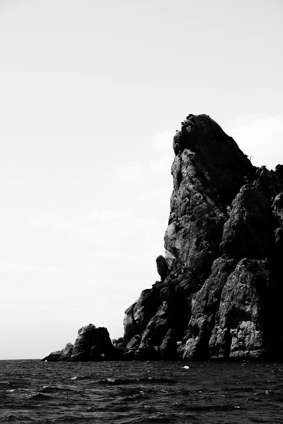 Rocky cliff face overlooking vast ocean with water stretching out to meet the sky