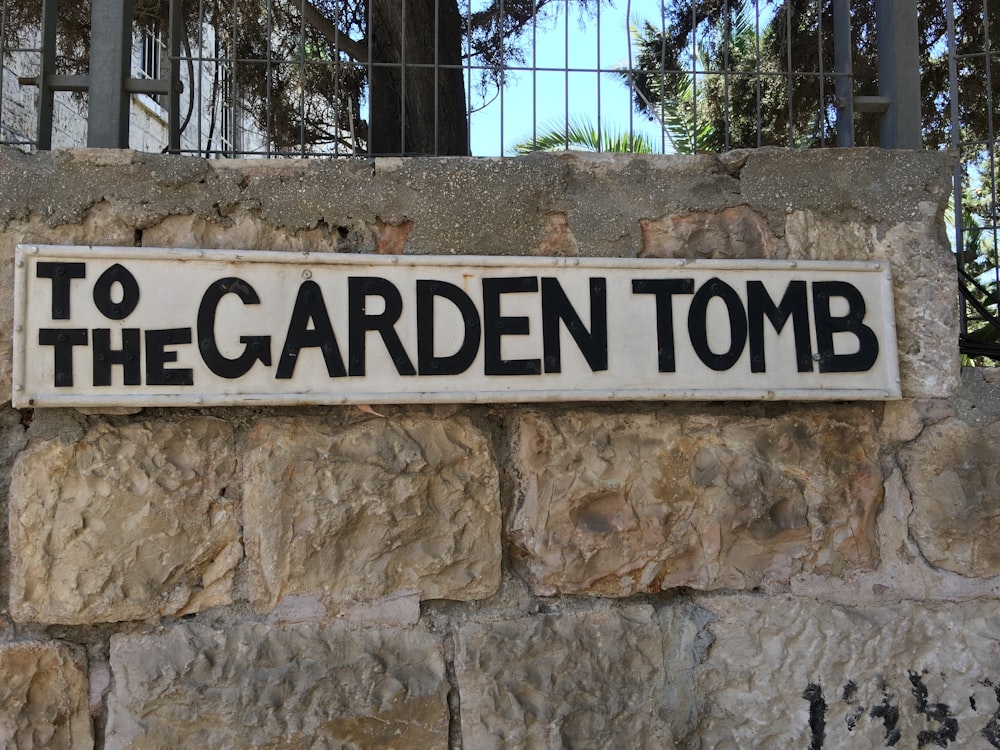 a sign on a stone wall that says to the garden tomb