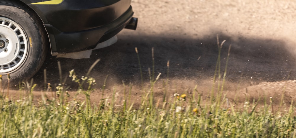 a car driving down a dirt road next to tall grass