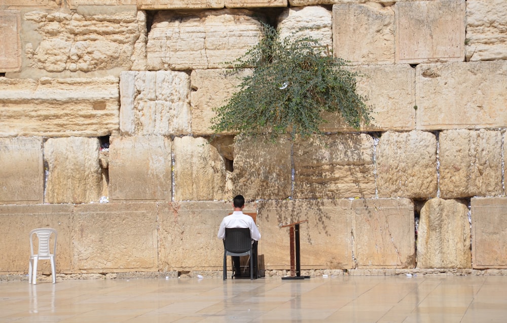 a man sitting at a table in front of a stone wall