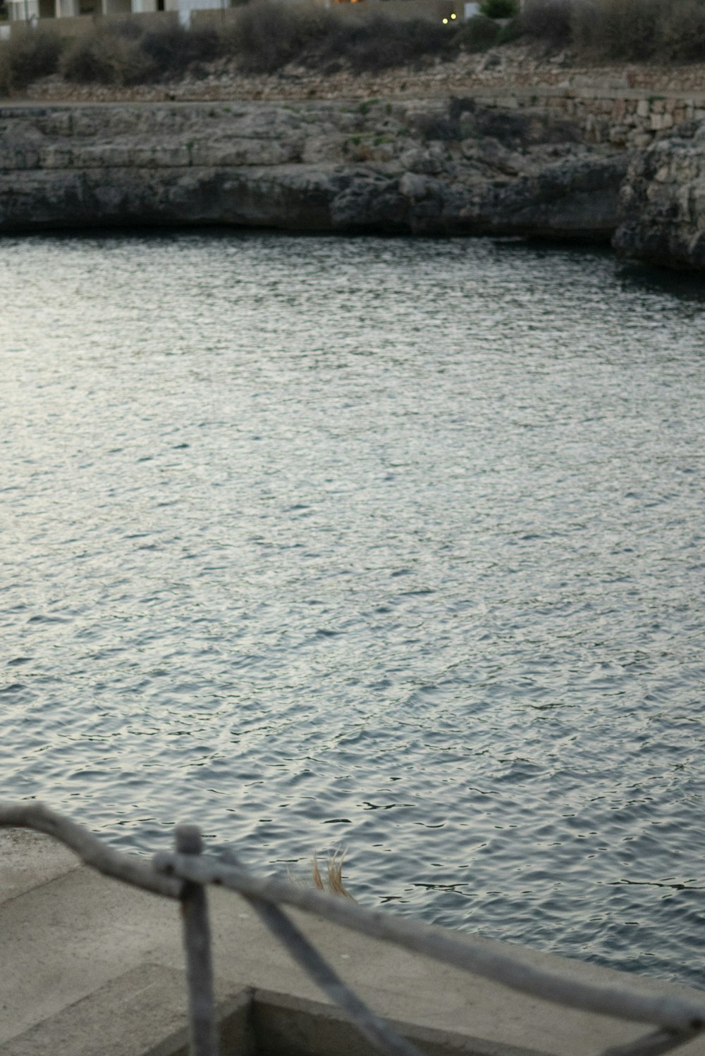 a man sitting on a bench next to a body of water