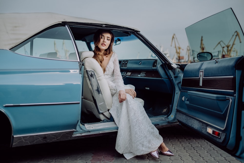 a woman sitting in the back of a blue car