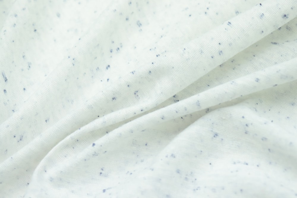 a close up of a white fabric with blue speckles