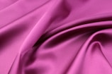 A handcrafted pink silk scarf draped softly, reflecting light and femininity.