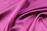 A close-up of a soft pastel pink silk saree draped elegantly over a wooden hanger.