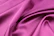 Close-up of an elegant royal pink silk saree shimmering under soft light.