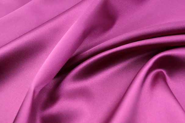 Close-up of the rose pink satin fabric catching the bright natural daylight, highlighting its smooth texture against the navy and indigo color scheme.