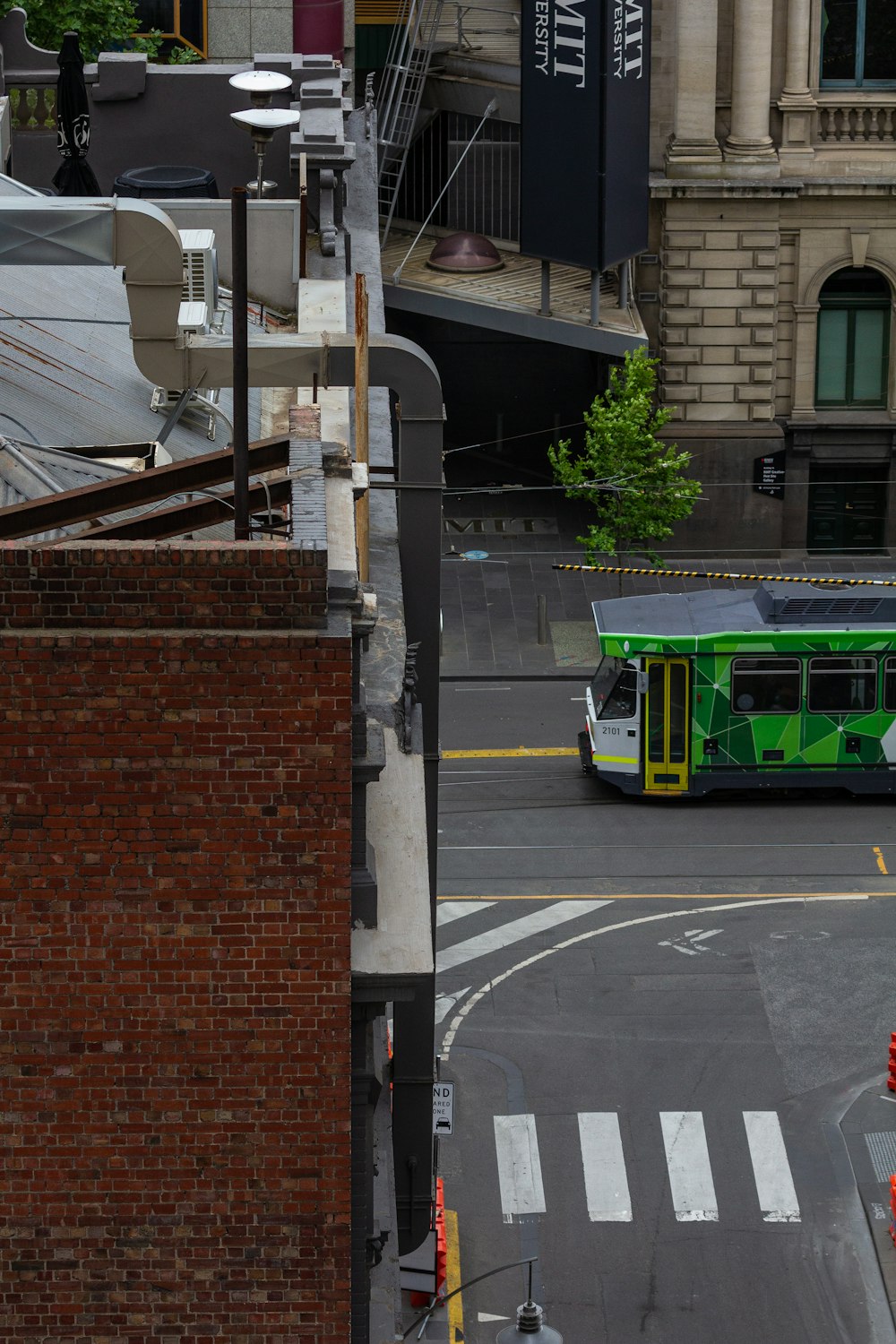 a green bus driving down a street next to a tall building