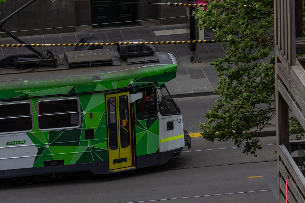 a green and white bus driving down a street