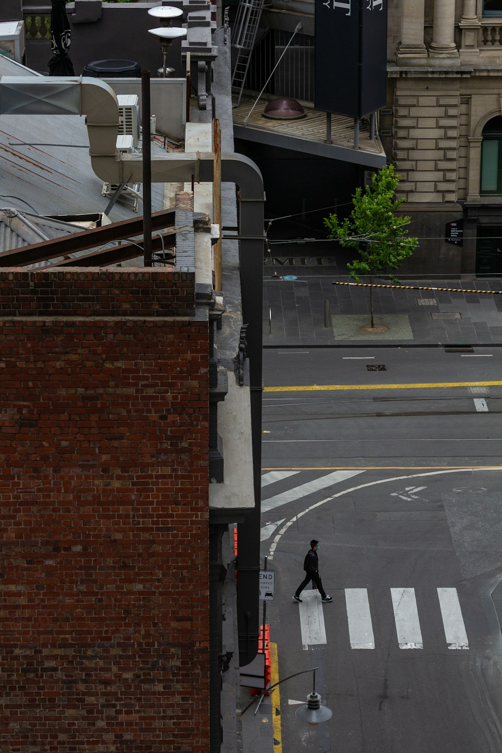 a man walking across a street next to a tall building