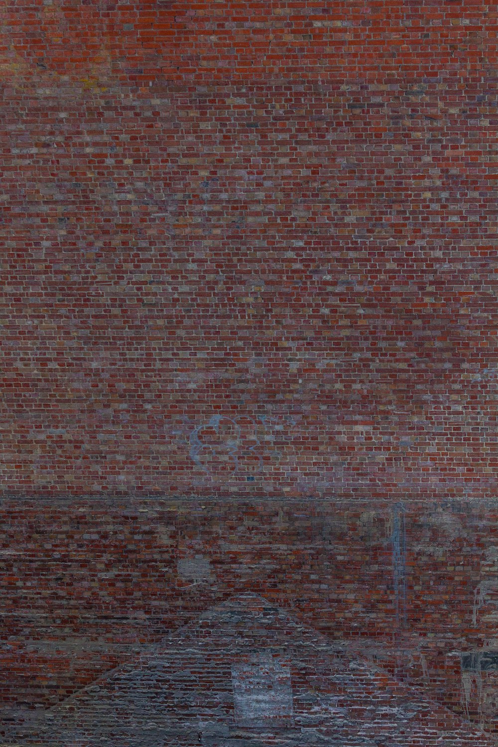 a man riding a skateboard down a street next to a tall brick wall