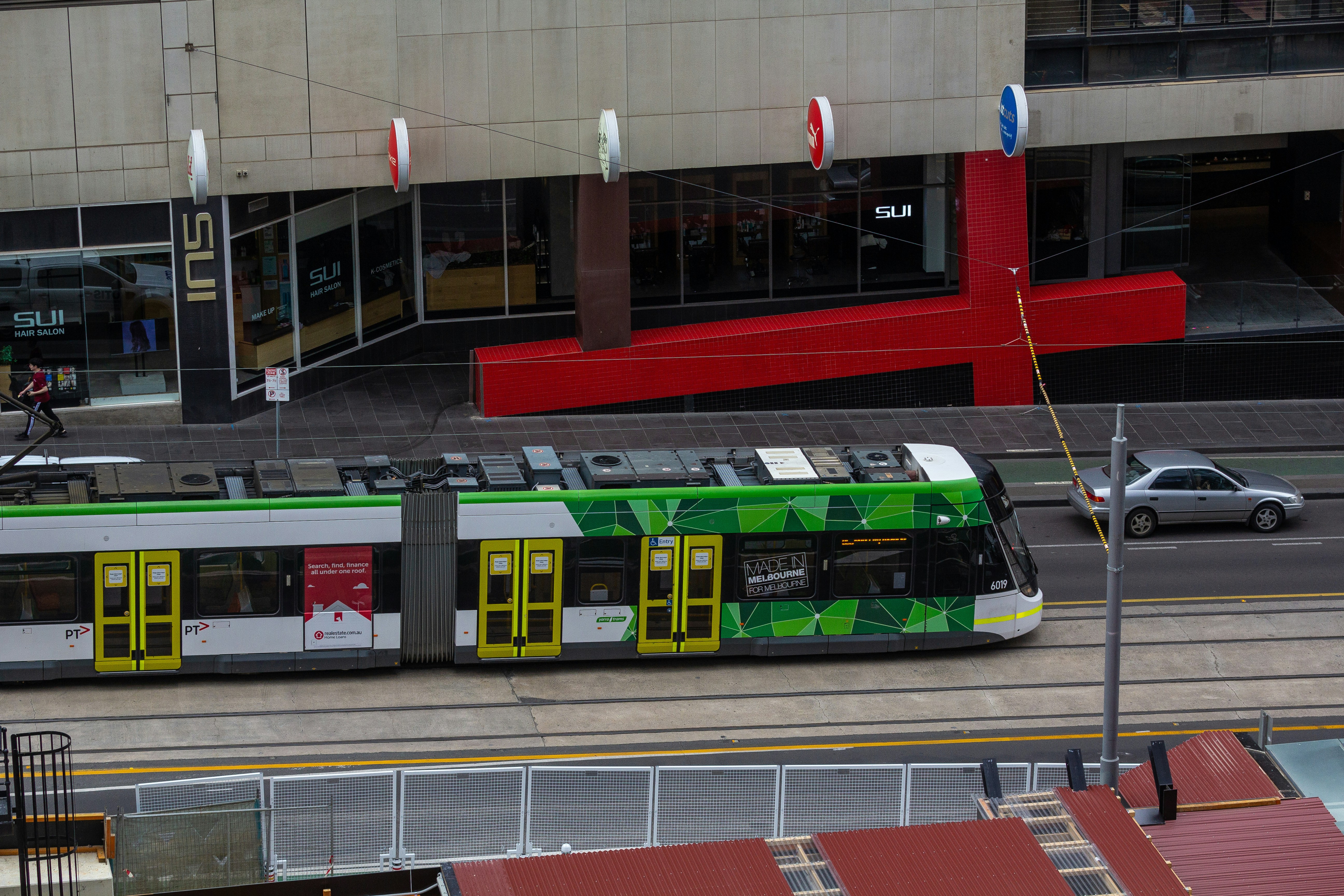 a green and white train traveling past a tall building