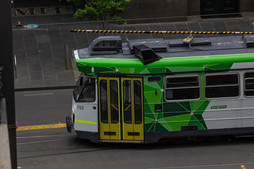 a green and white bus driving down a street