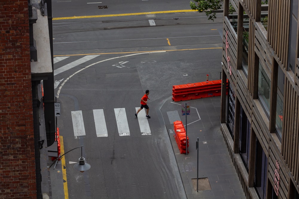 a man walking across a street next to a tall building