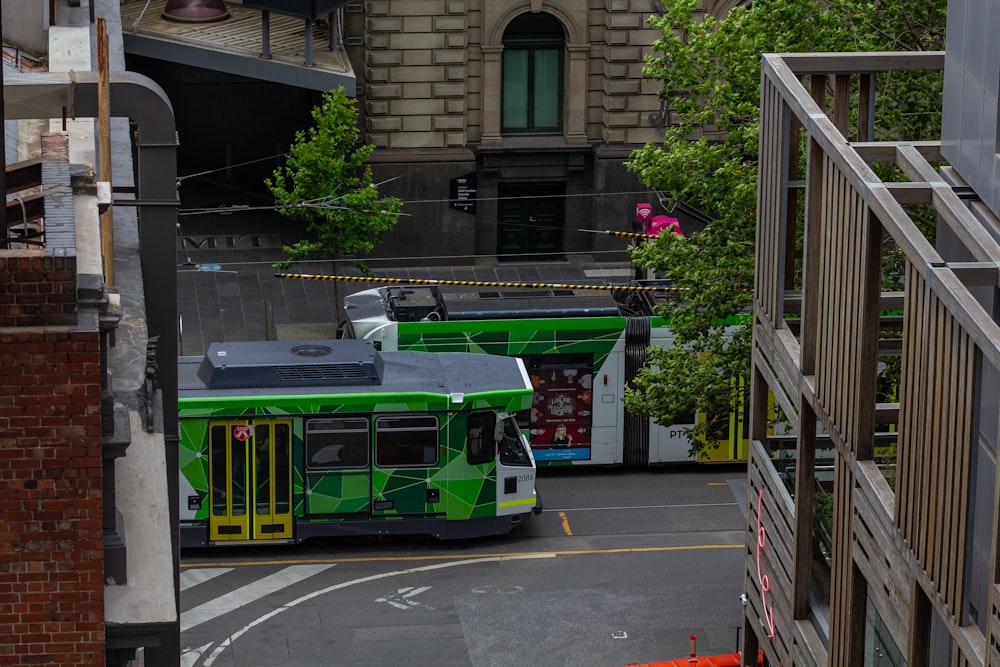 a green bus driving down a street next to a tall building