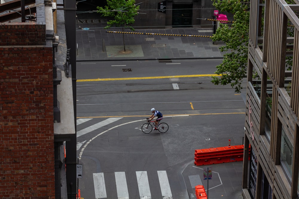 a man riding a bike down a street next to tall buildings