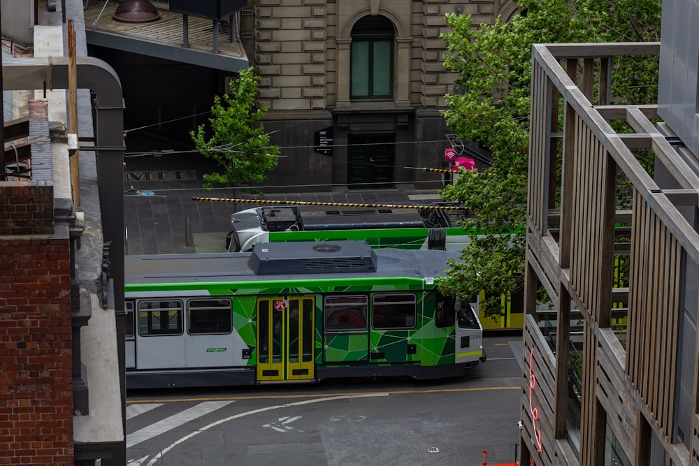 a green and white bus driving down a street next to a tall building