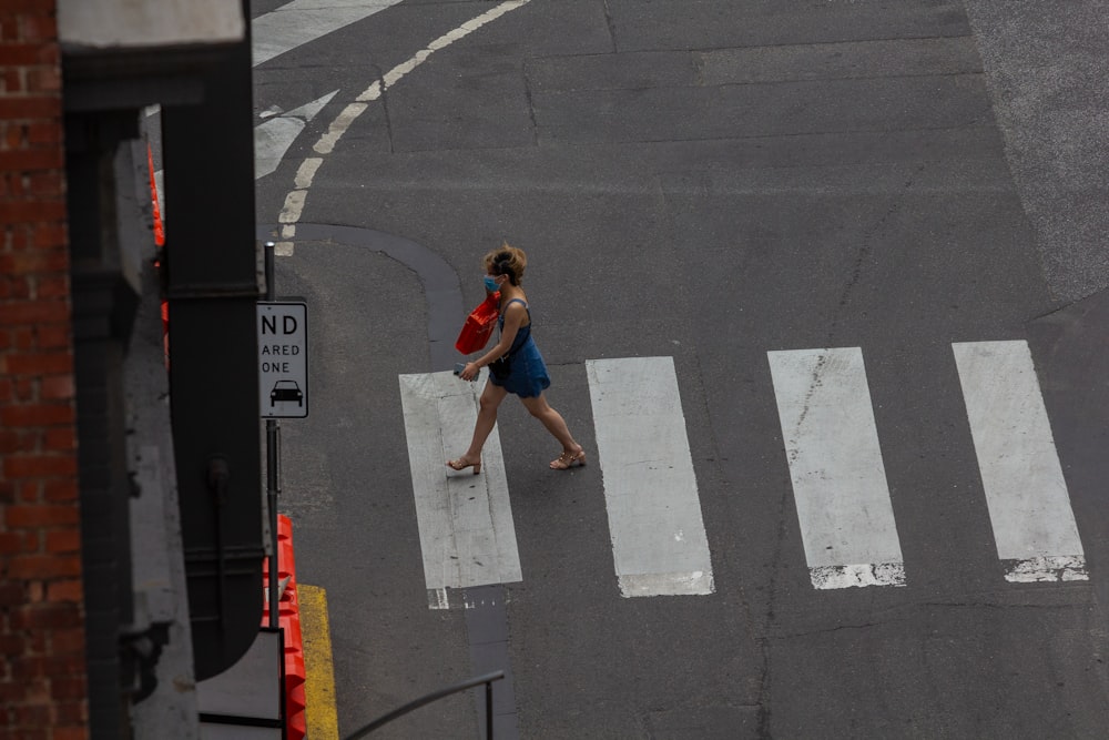 a woman walking across a street next to a cross walk