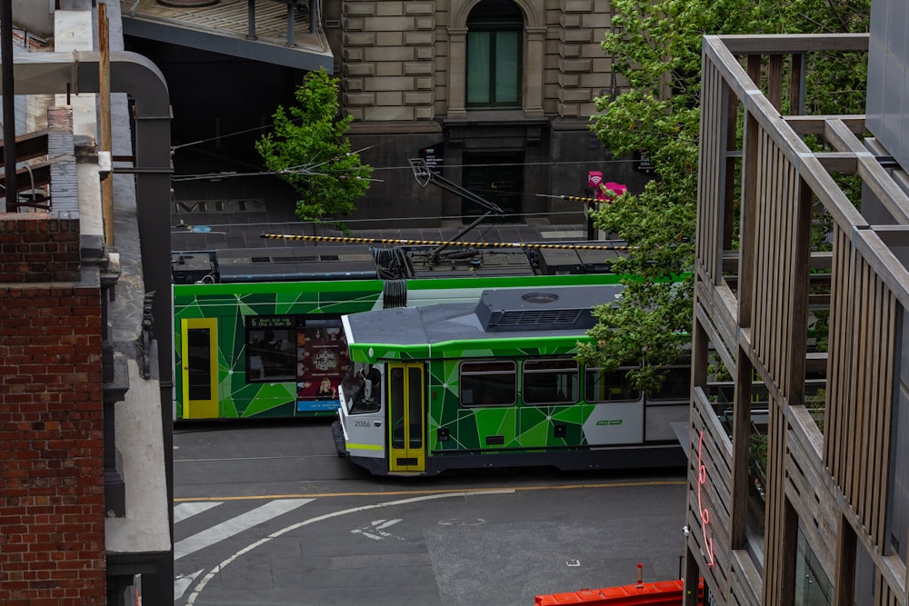 a green and white bus driving down a street next to tall buildings