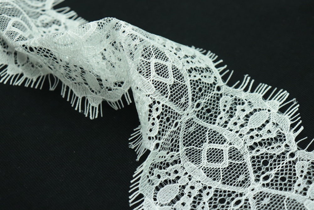 a close up of a white lace on a black background