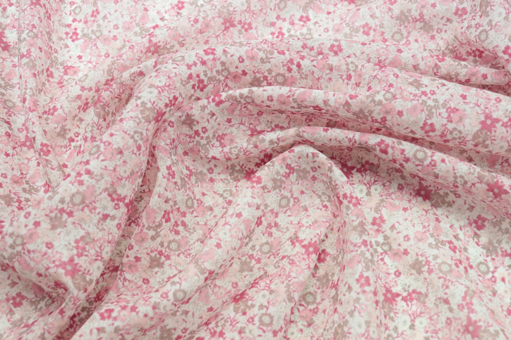 a close up of a pink and white flowered fabric