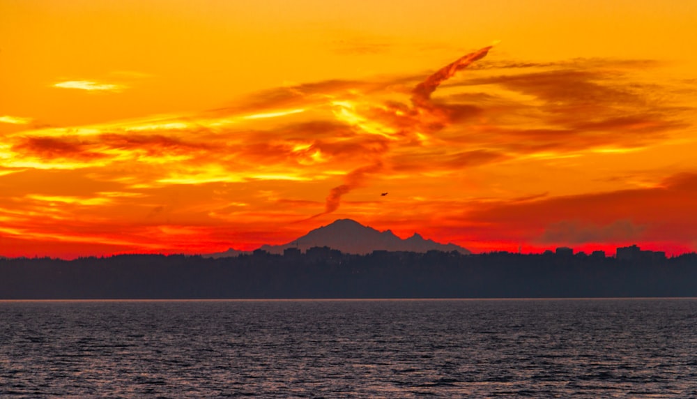 a beautiful sunset over a lake with a mountain in the distance