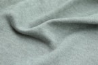 Close-up of a soft crew neck t-shirt with a subtle printed design, laid flat on a textured fabric background.