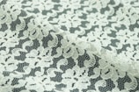 Intricate floral lace fabric with a delicate, sheer texture. The lace features an intricate pattern of flowers and leaves, with a mix of open and dense areas creating a sense of transparency.