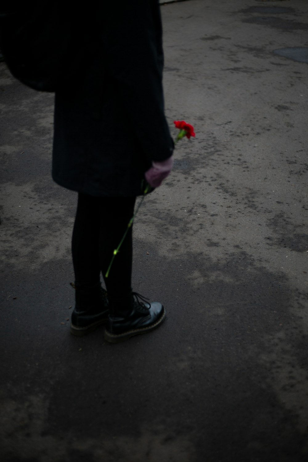 a person standing on a street holding a flower