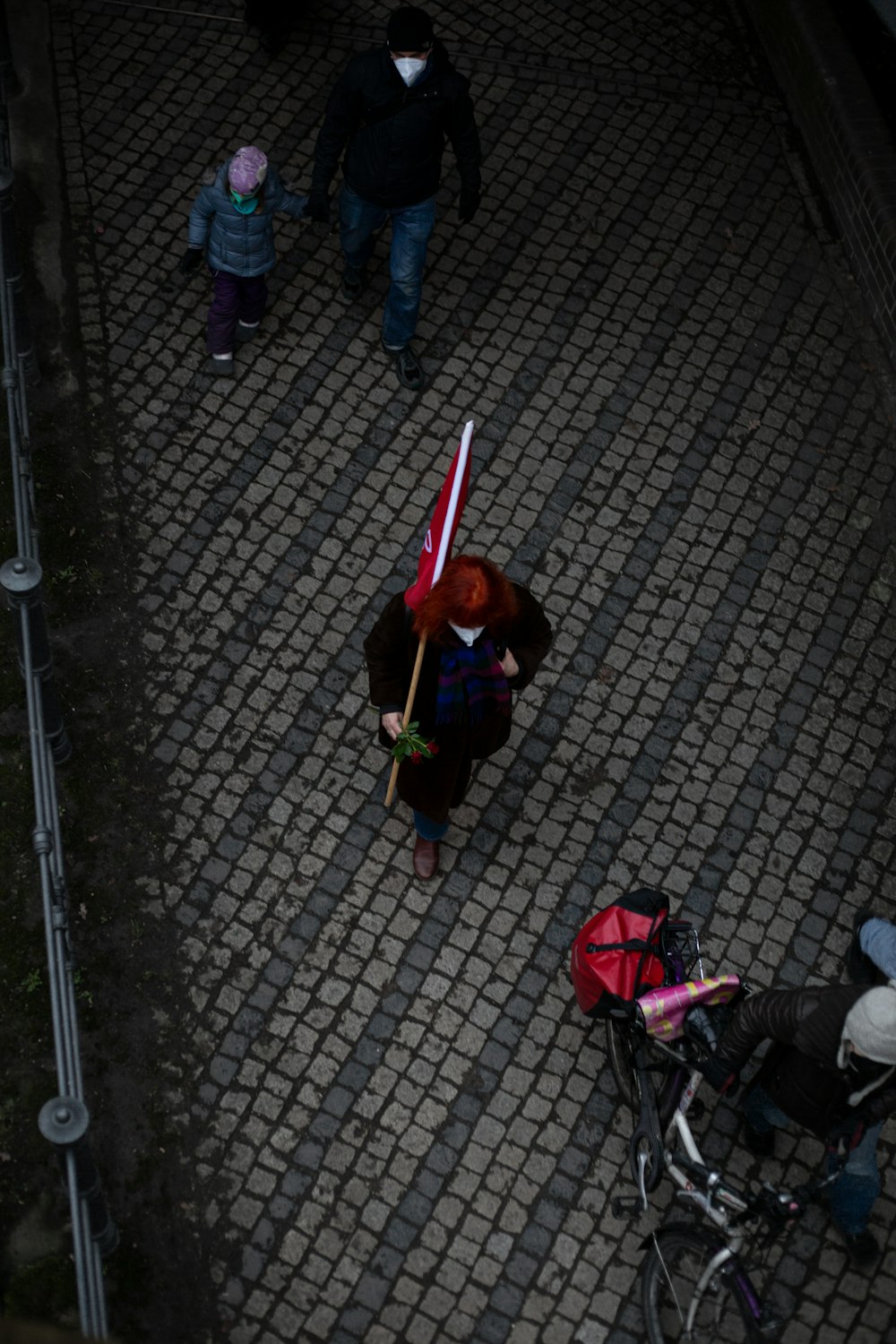 a woman walking down a street holding a red and white flag