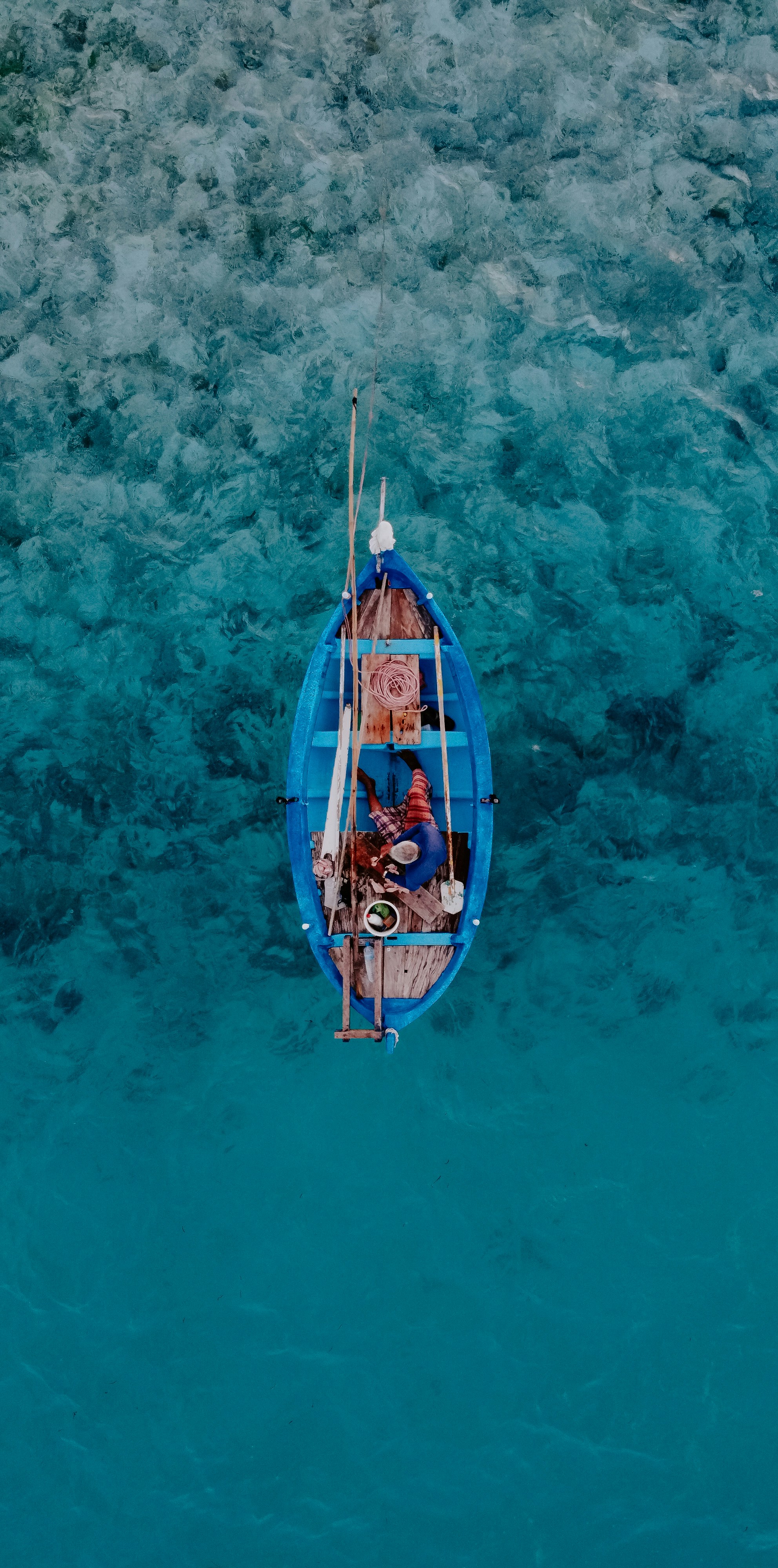 una piccola barca blu che galleggia sulla cima di uno specchio d'acqua