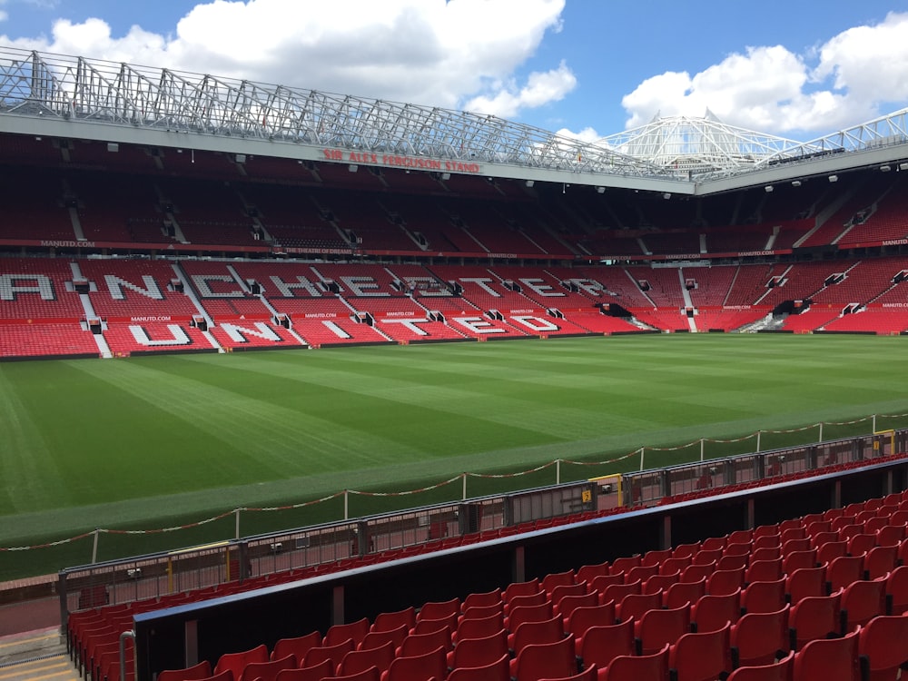 an empty stadium with red seats and a green field